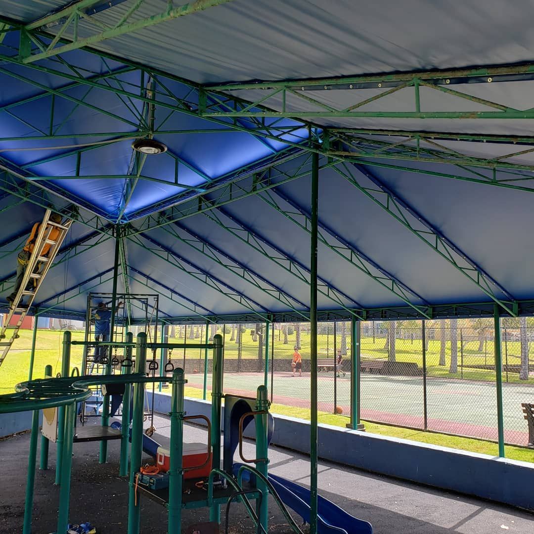 A playground under a blue tent with a slide and stairs