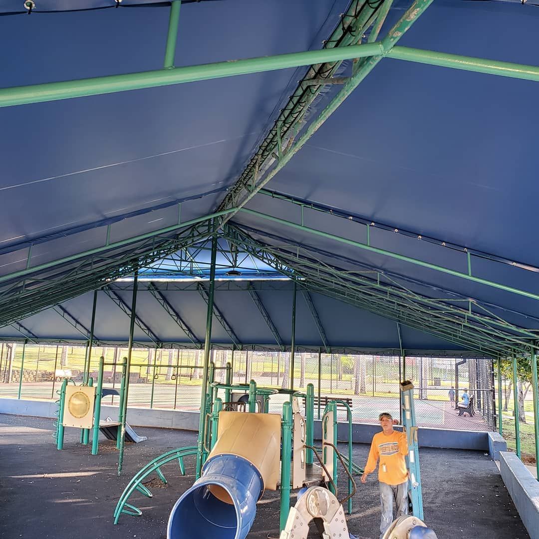 Children are playing in a playground under a blue canopy
