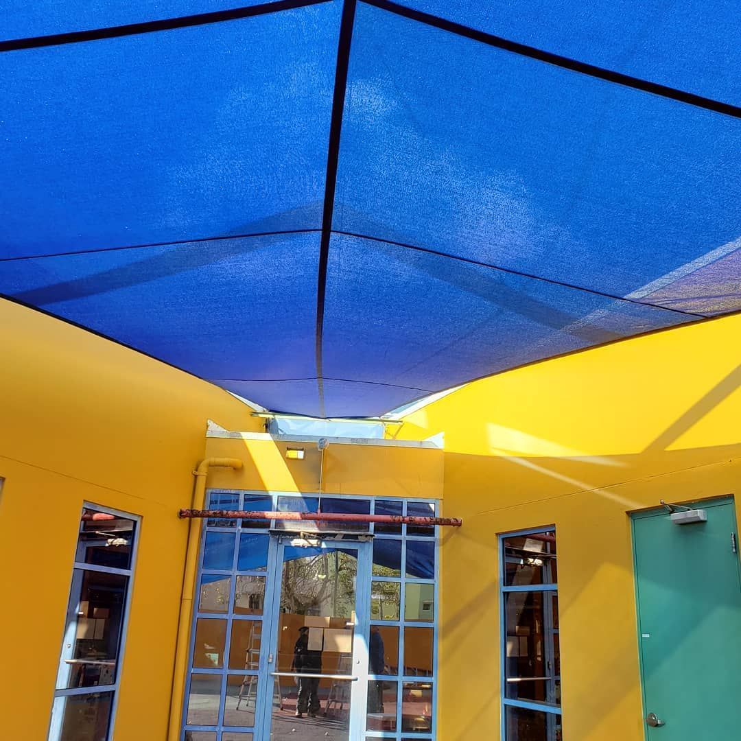 A yellow building with a blue umbrella over it