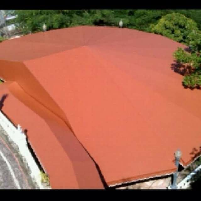 An aerial view of a red roof with trees in the background