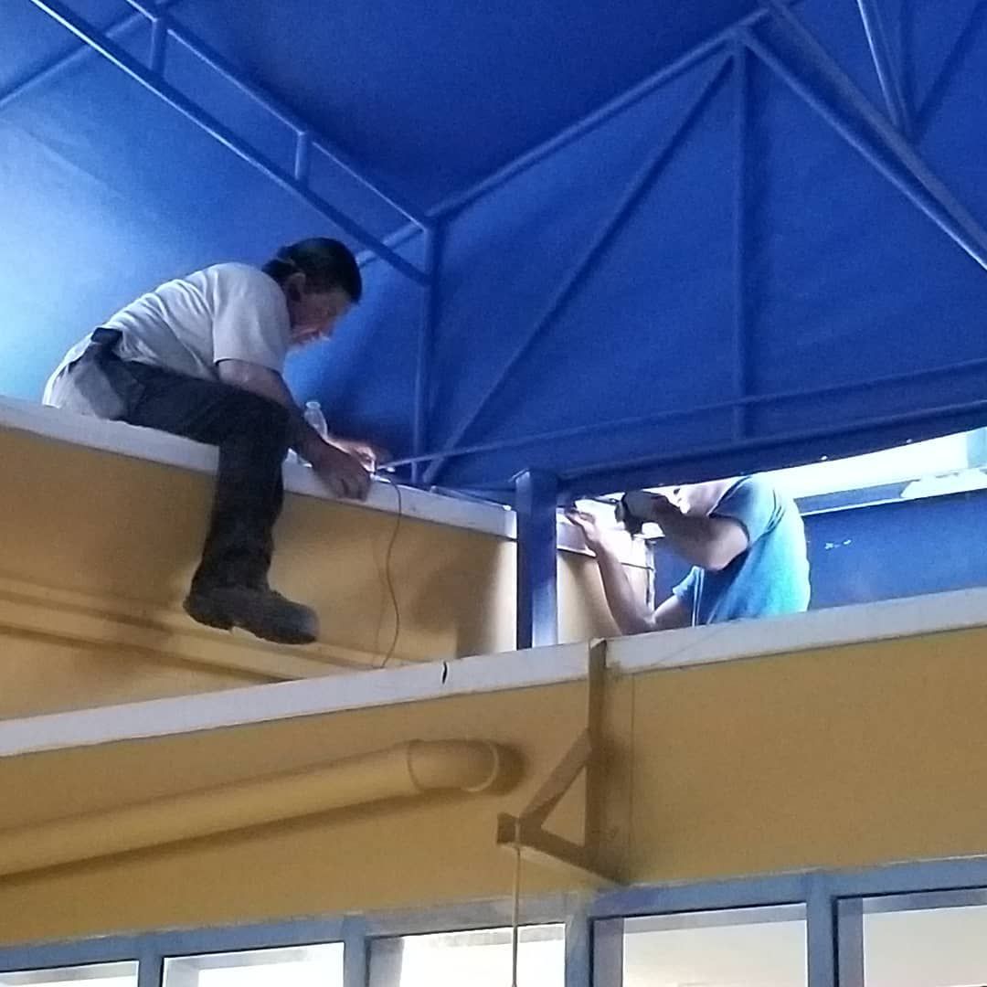 Two men are working on a building with a blue roof