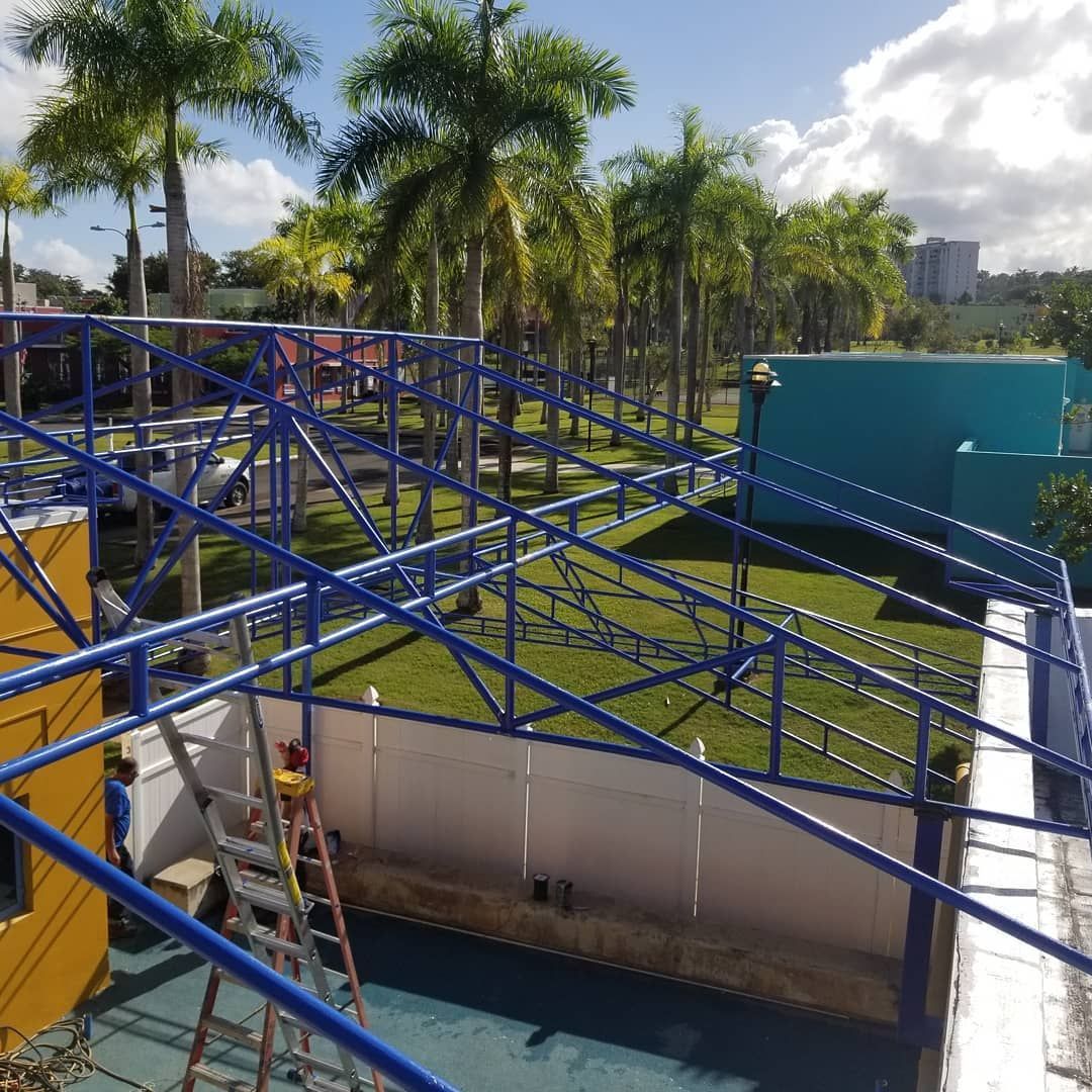 A large blue structure is surrounded by palm trees