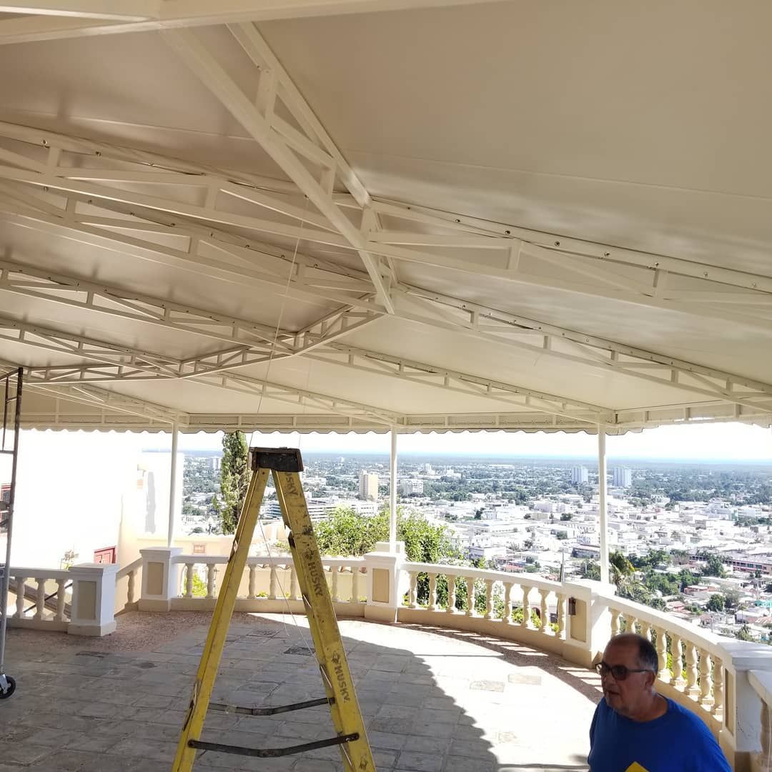 A man sitting under a canopy with a ladder in front of him