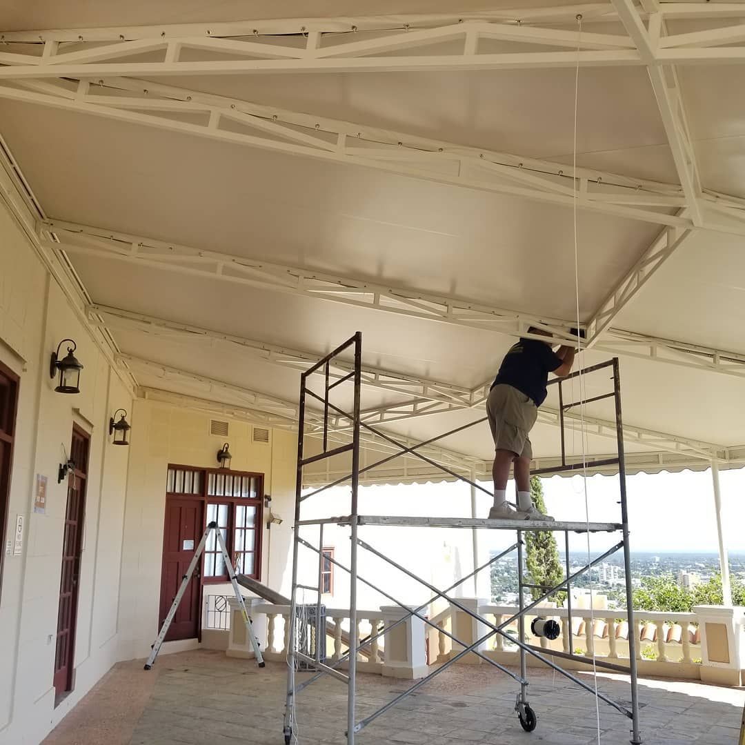 A man is standing on a scaffolding working on the ceiling of a building
