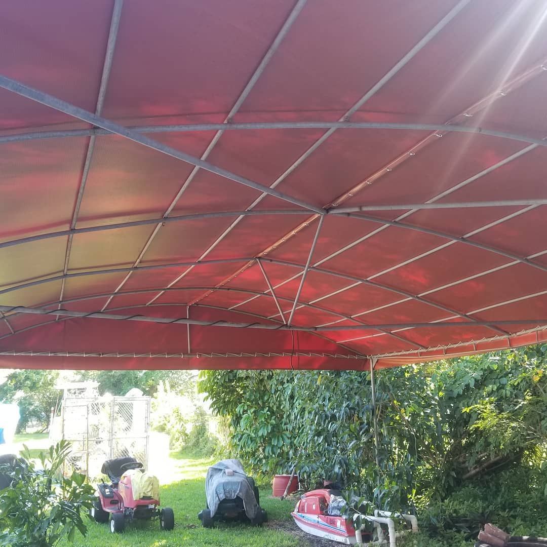 A red tent with a lawn mower underneath it