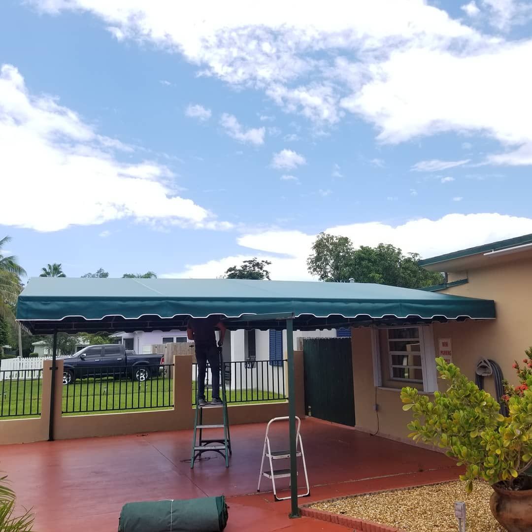 A green awning is being installed on the side of a house