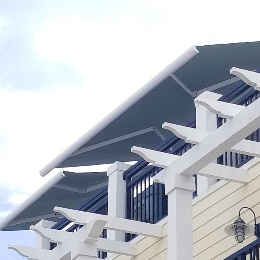 A white pergola with a blue awning on top of it