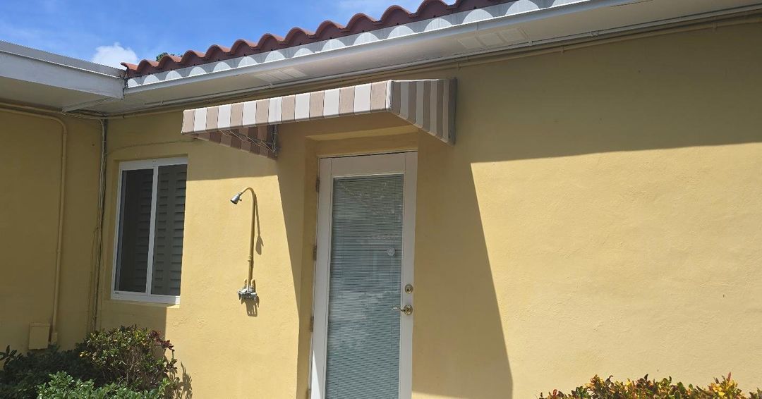 A yellow house with a white awning over the door.