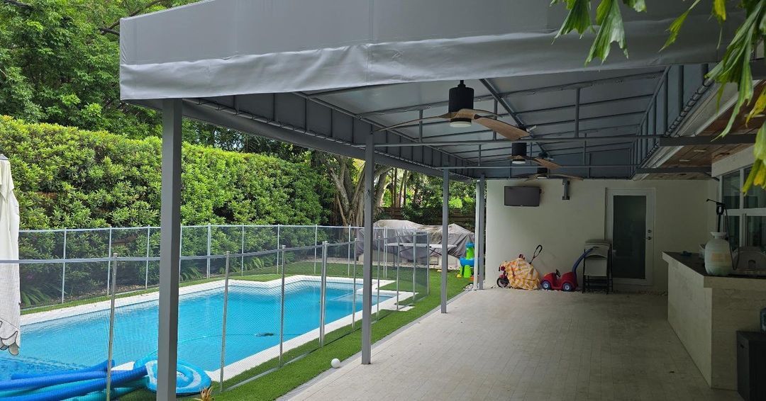 A large covered patio with a swimming pool in the background.