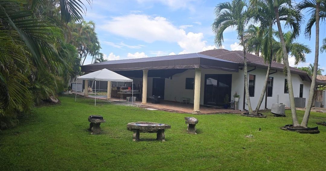 A large house with a large lawn in front of it surrounded by palm trees.