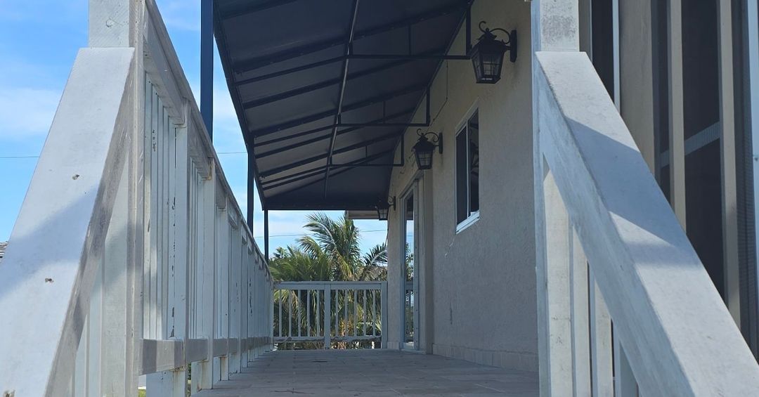 A white railing leads to a porch with a canopy over it.