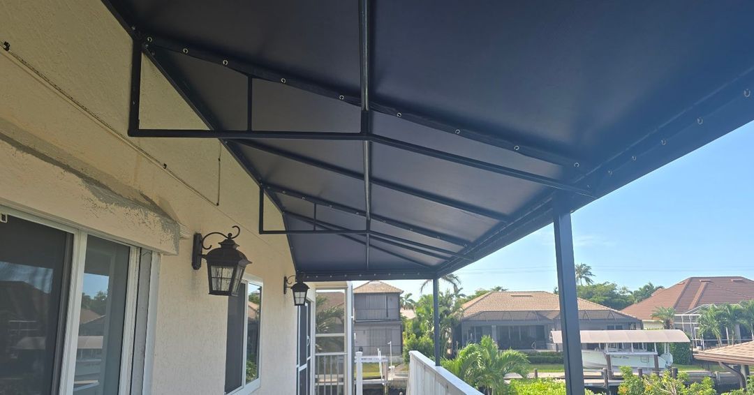 A porch with a canopy over it and a light on the side of the house.