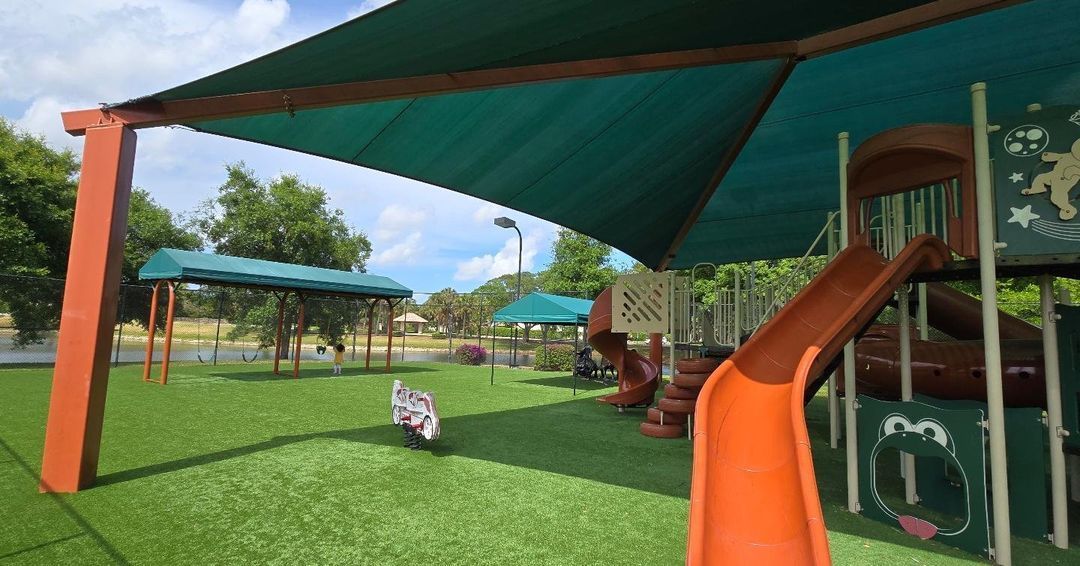 A playground with a slide and a canopy in a park.