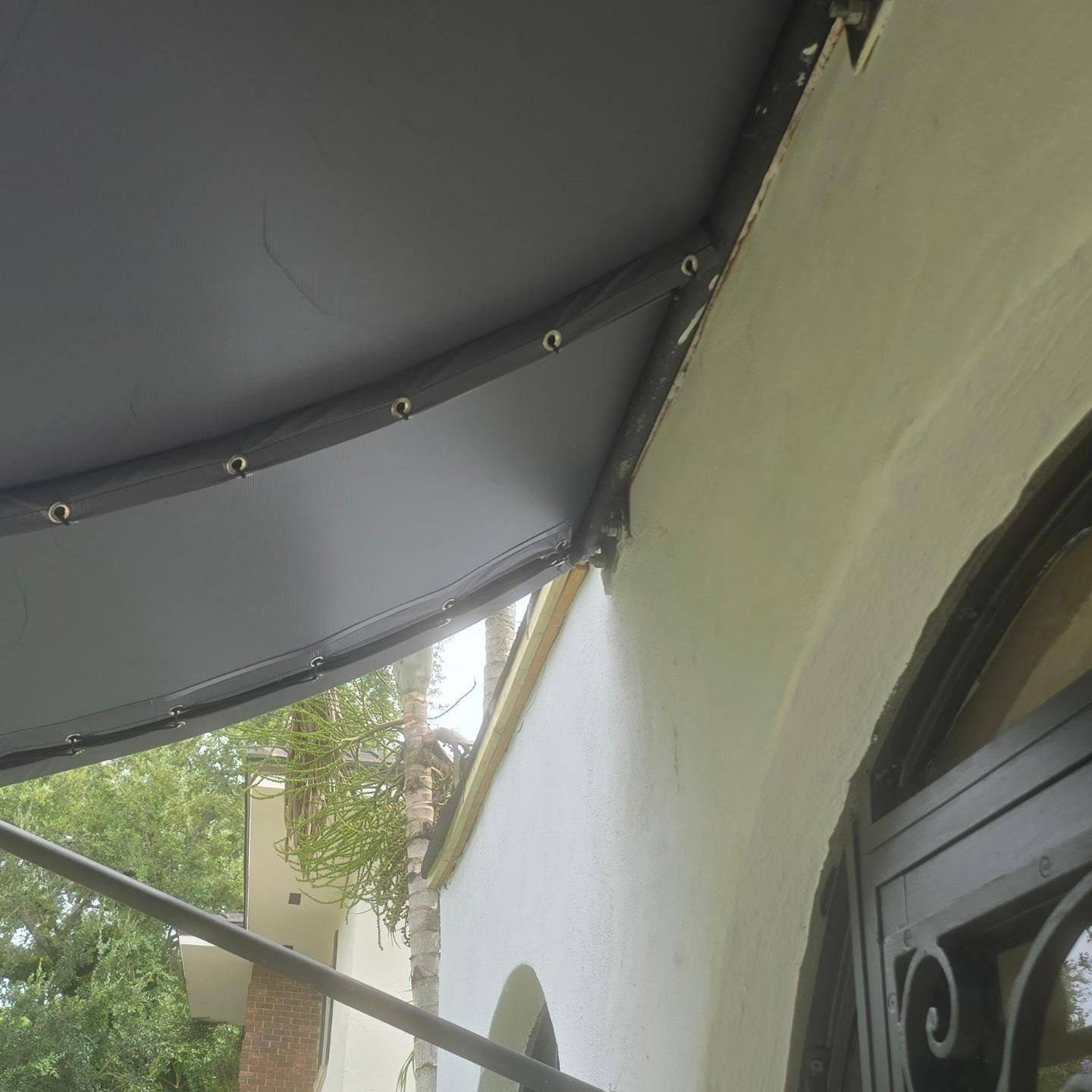 A gray awning is hanging from the side of a building