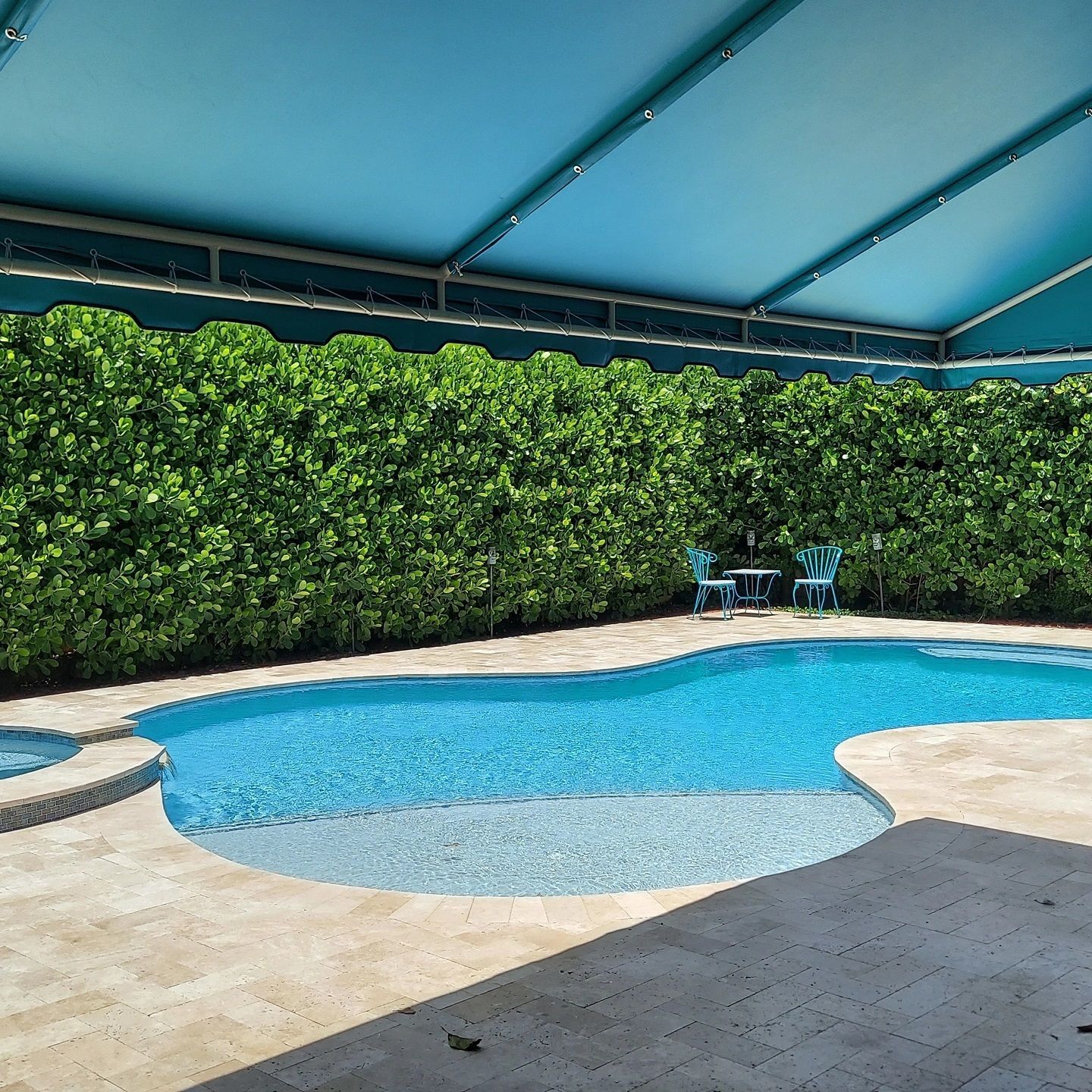 A large swimming pool with a blue awning over it
