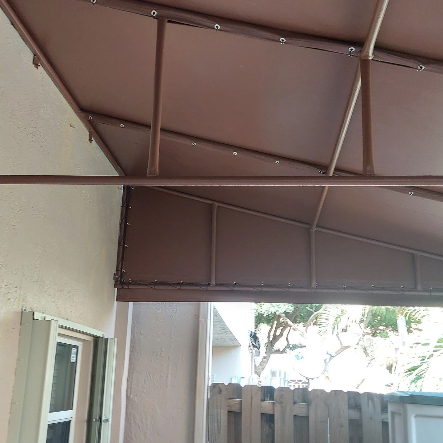 A brown awning with a fence in the background