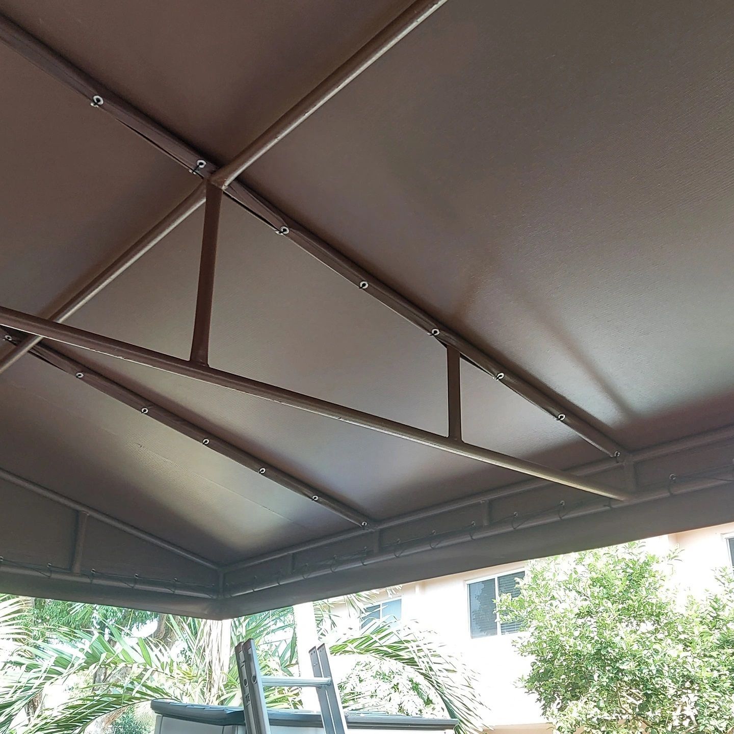 A ladder is sitting underneath a brown canopy.