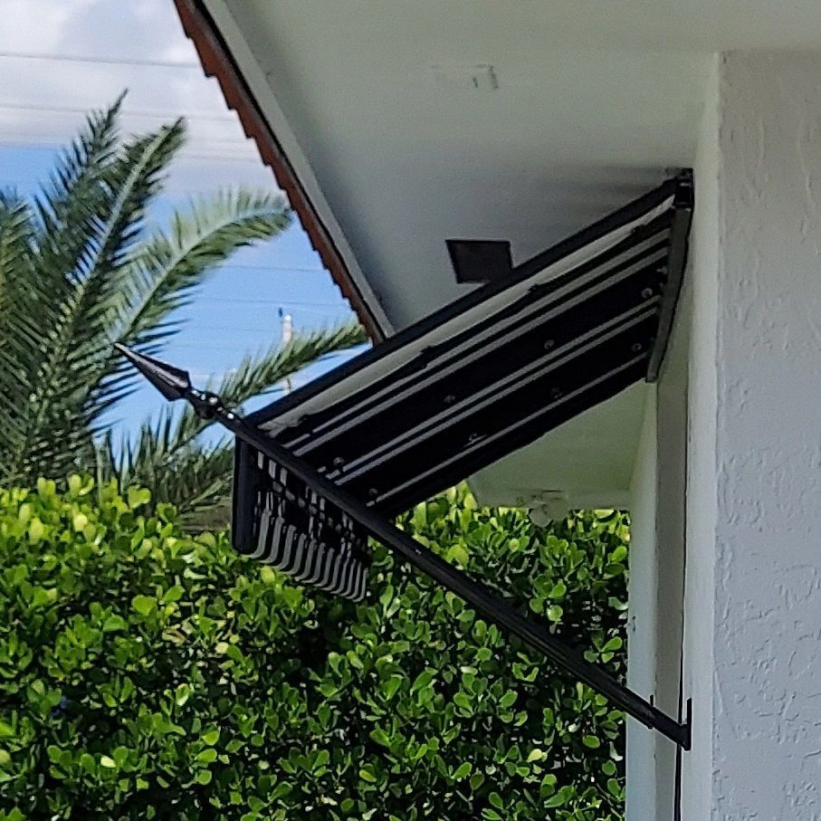 A black awning is hanging from the side of a white building.