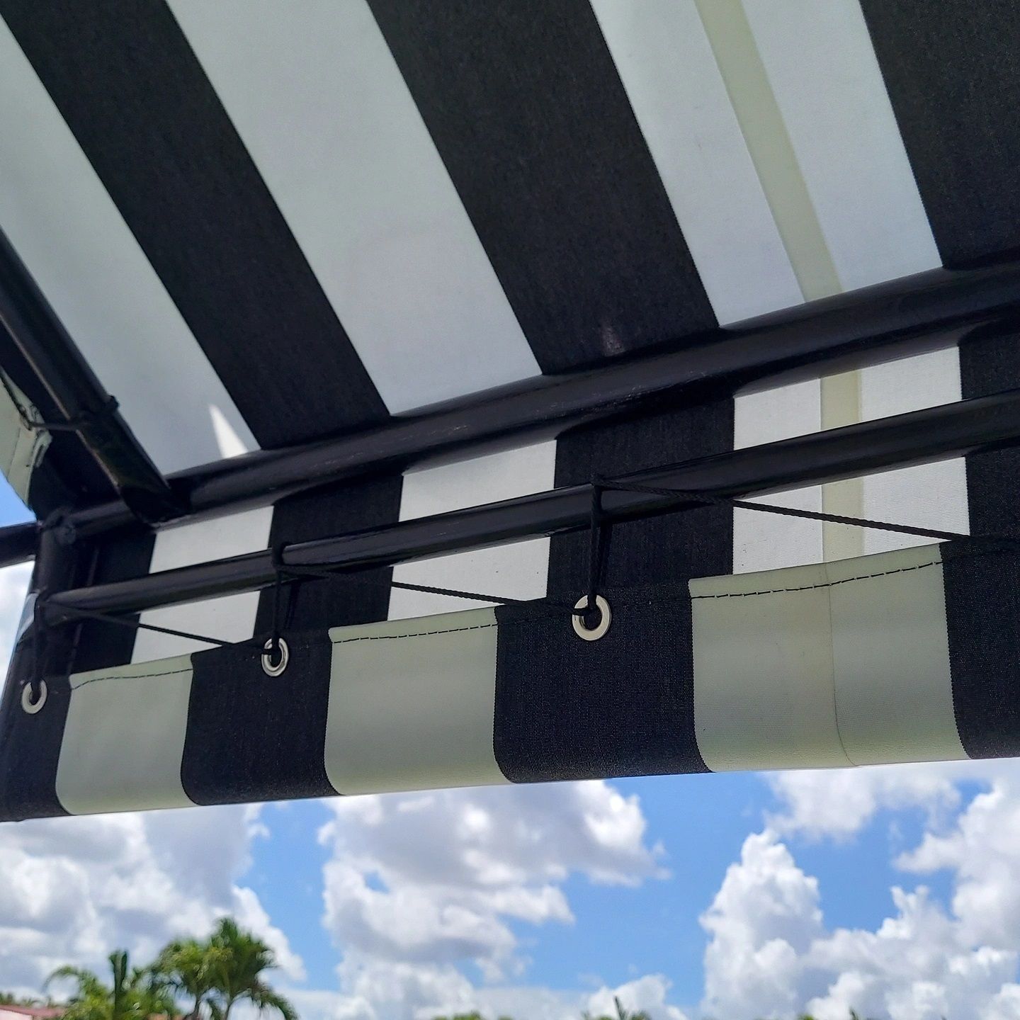 A black and white striped awning with a blue sky in the background