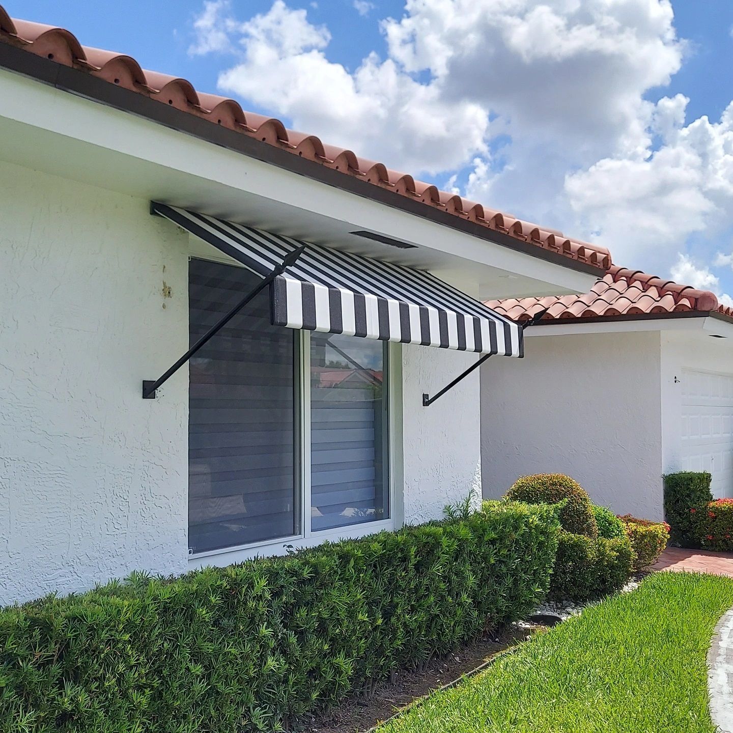 A white house with a black and white striped awning over a window