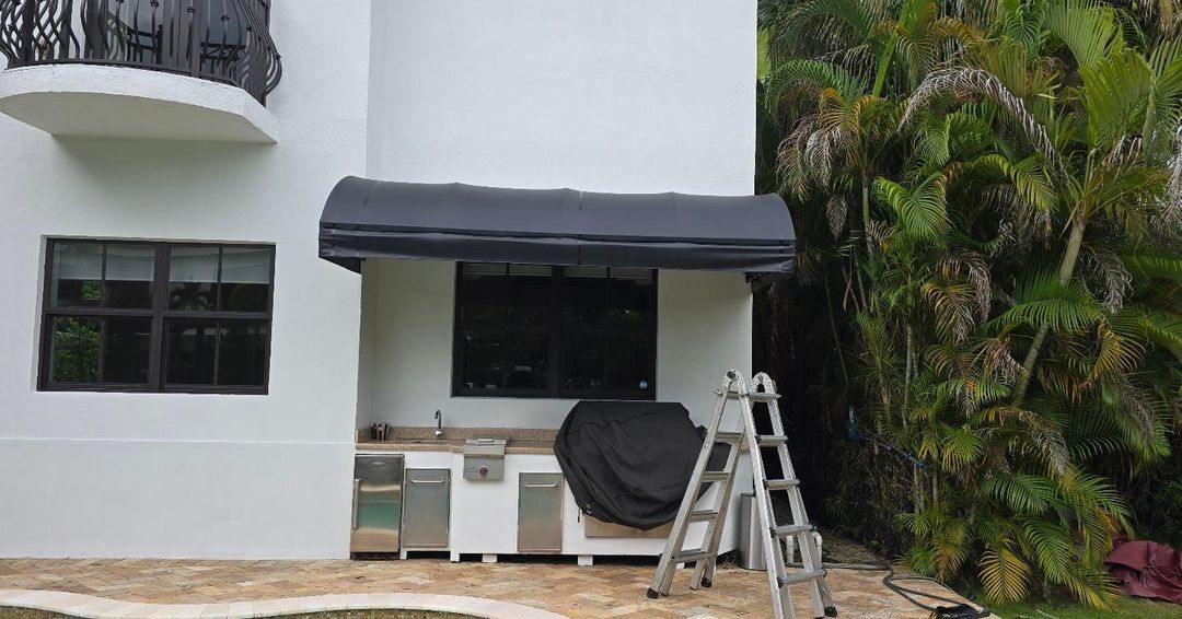 A white house with a black awning on the side of it.