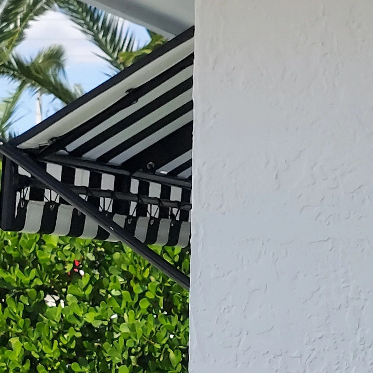 A black and white striped awning is on the side of a white building