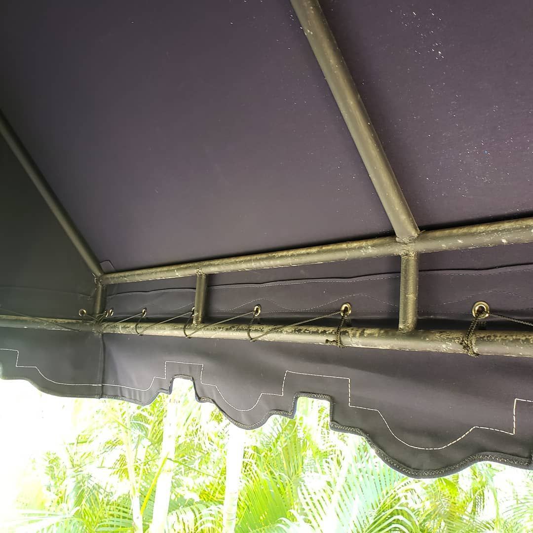 A close up of a purple awning with trees in the background.