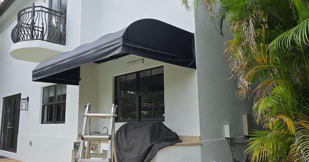 A white house with a black awning on the front of it.