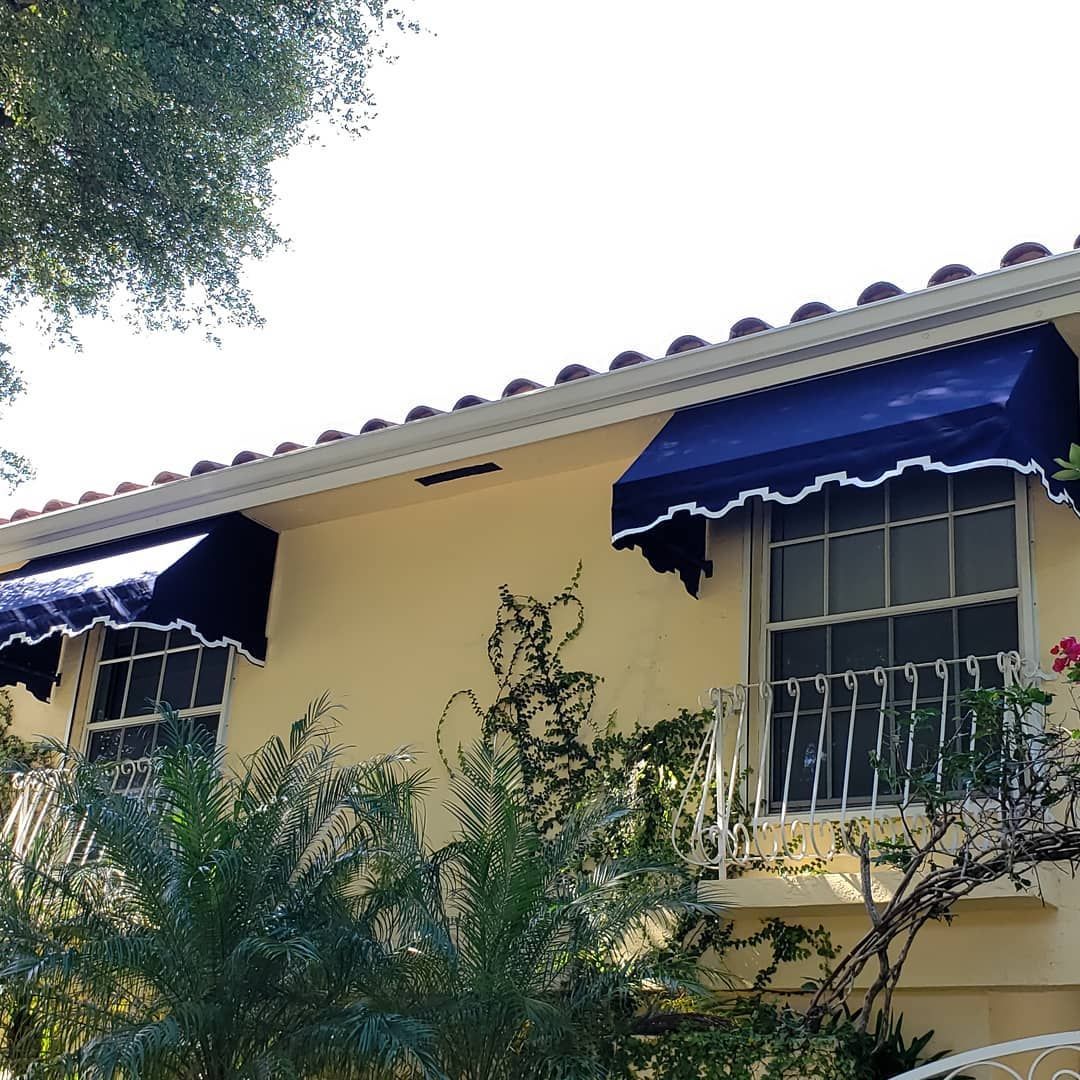 A yellow house with blue awnings on the windows
