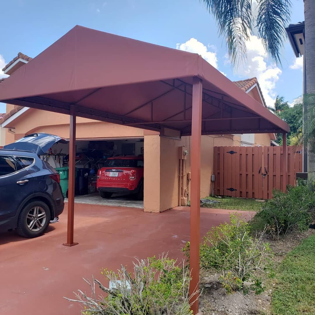 A car is parked under a canopy in front of a house.