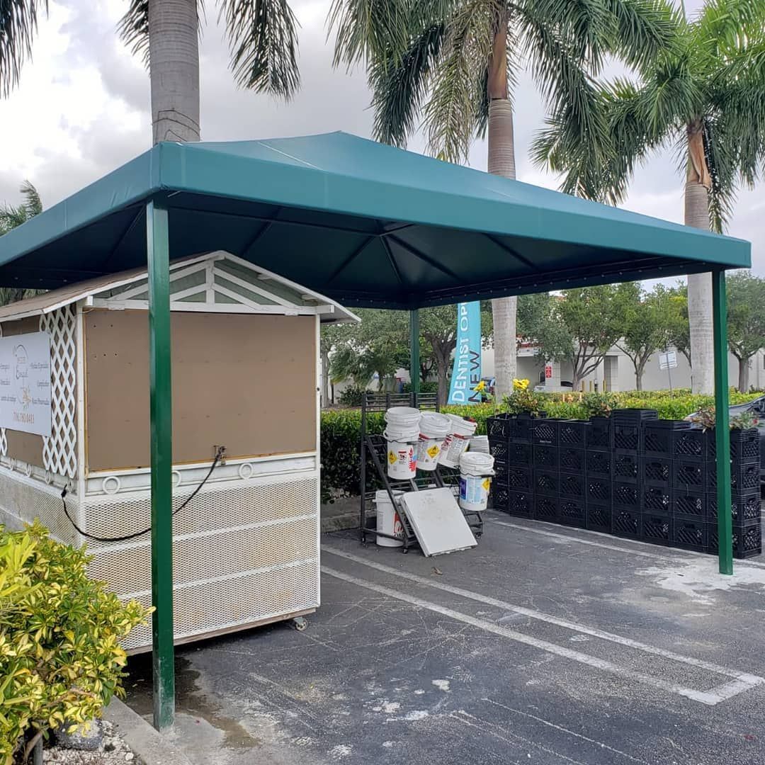 A green canopy is sitting in a parking lot next to a building.