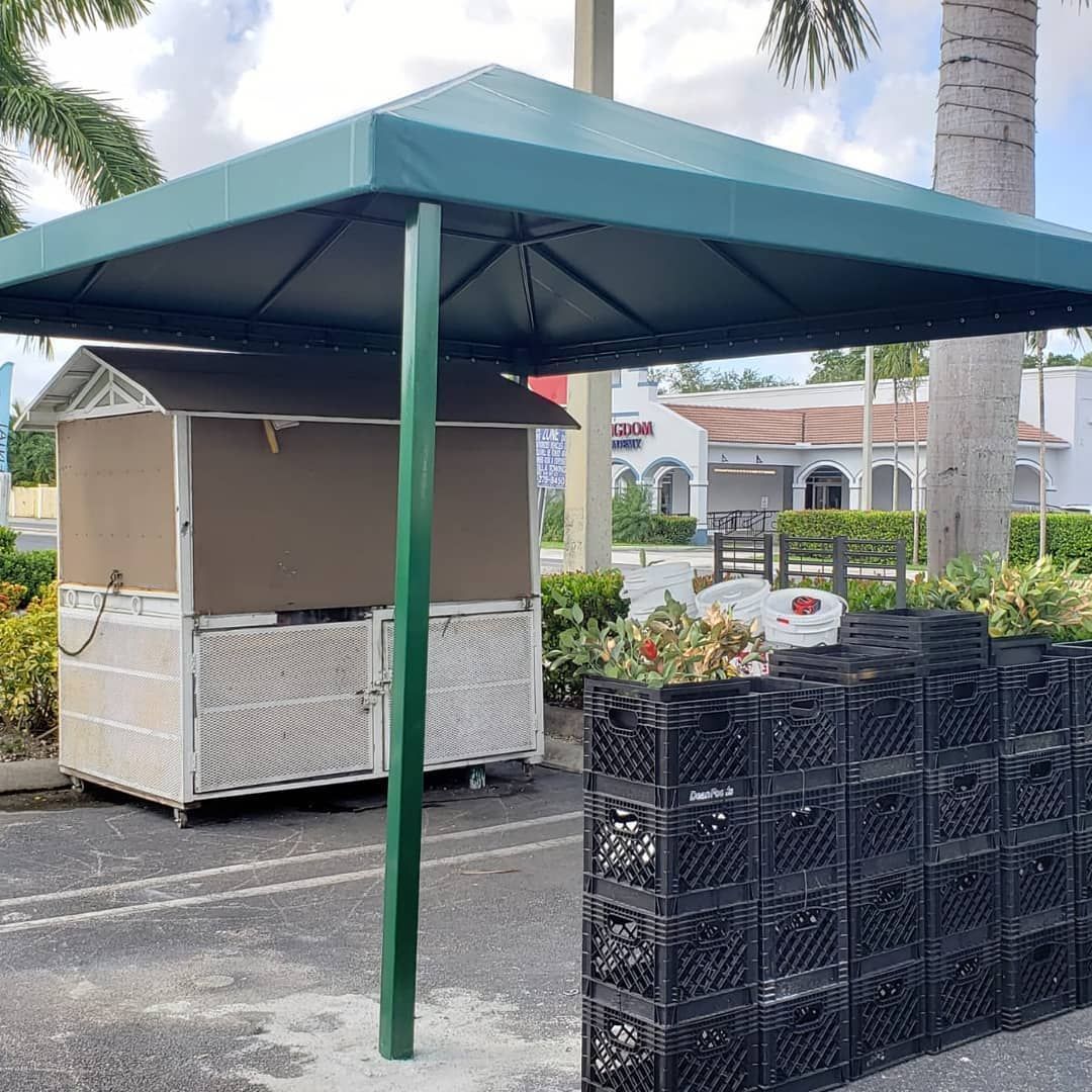 A shed with a green canopy is sitting next to a row of milk crates.