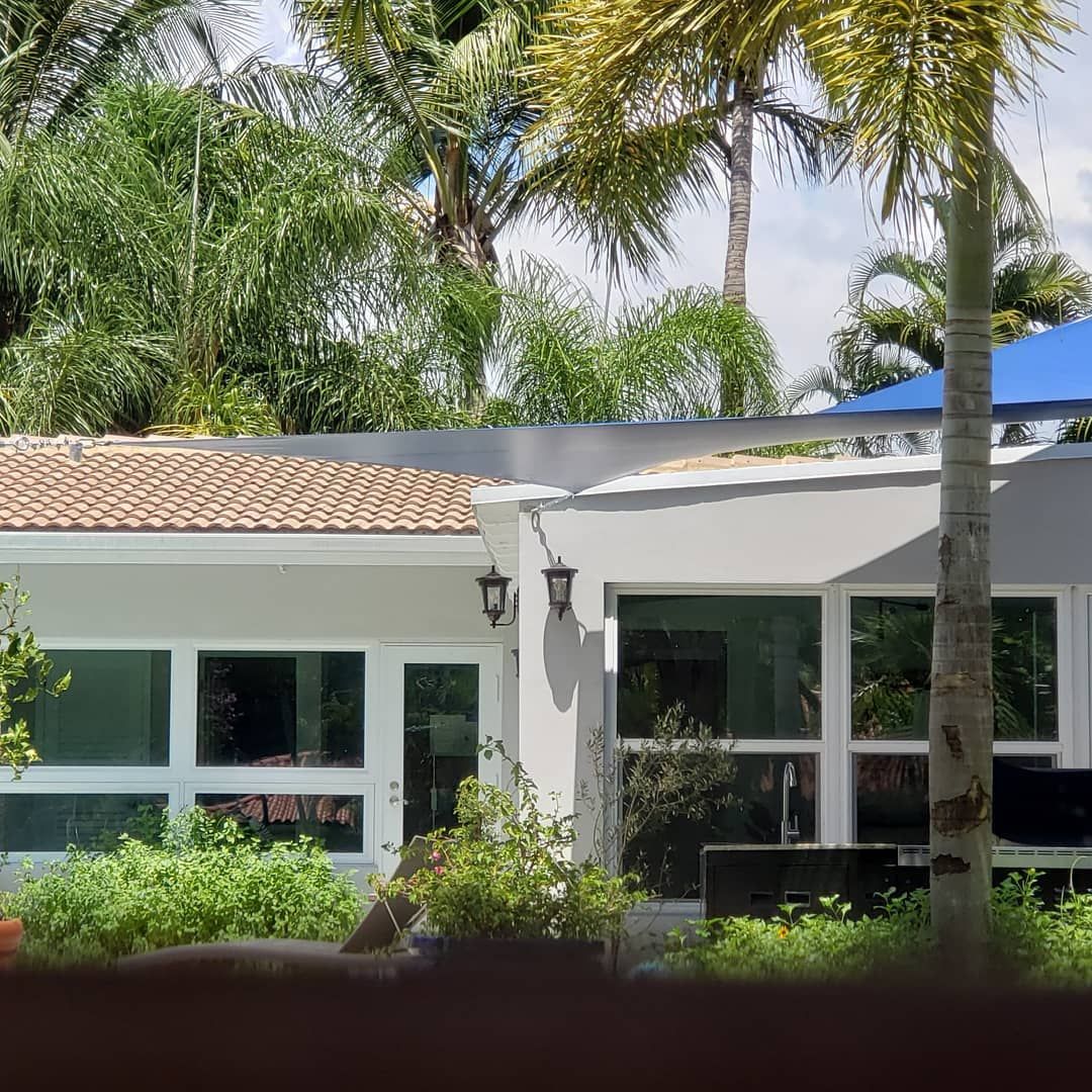 A white house with a blue umbrella and palm trees in the background.
