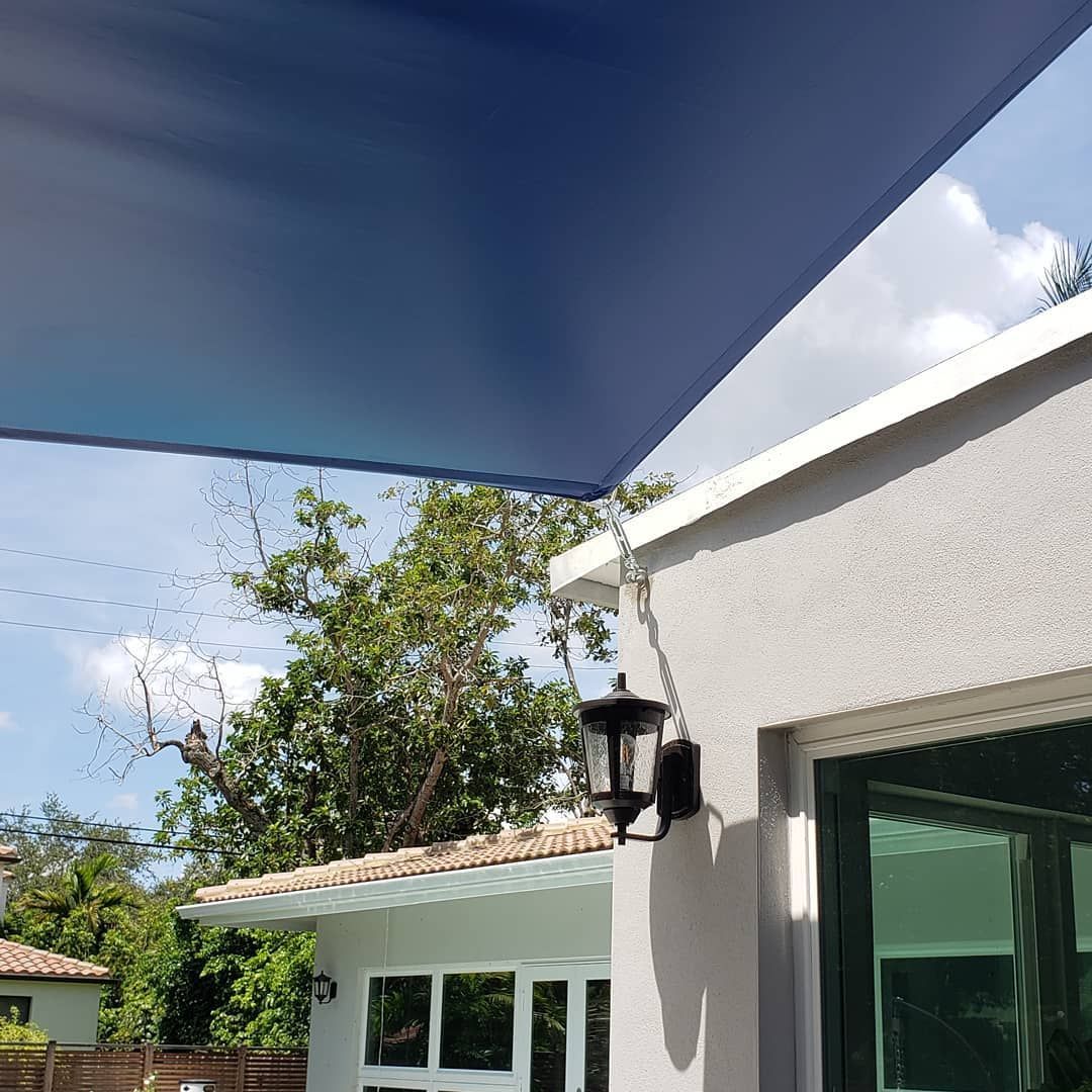 A blue umbrella is hanging from the roof of a house.
