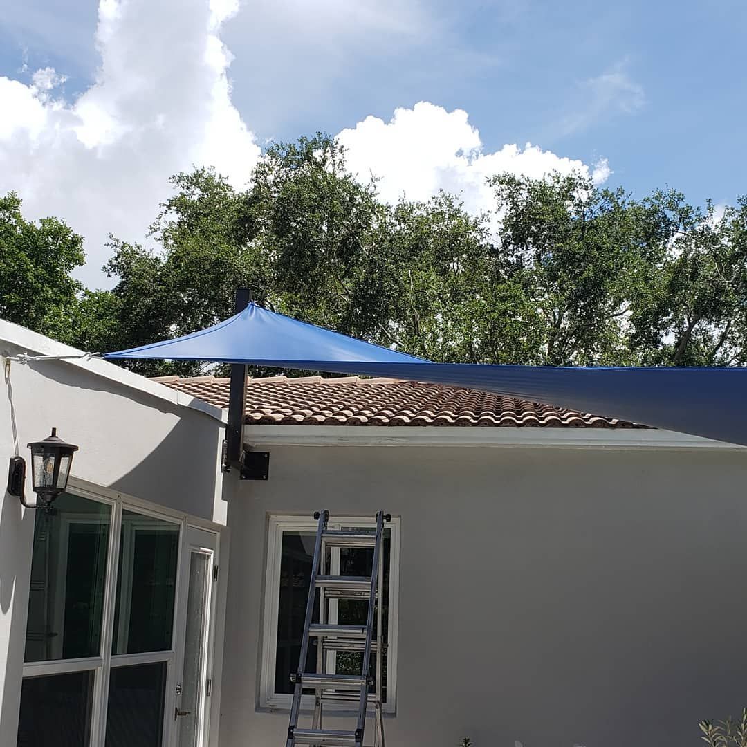 A blue umbrella is hanging from the roof of a house.