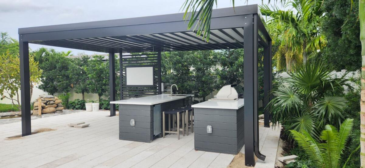 A patio with a pergola and a kitchen in the backyard.