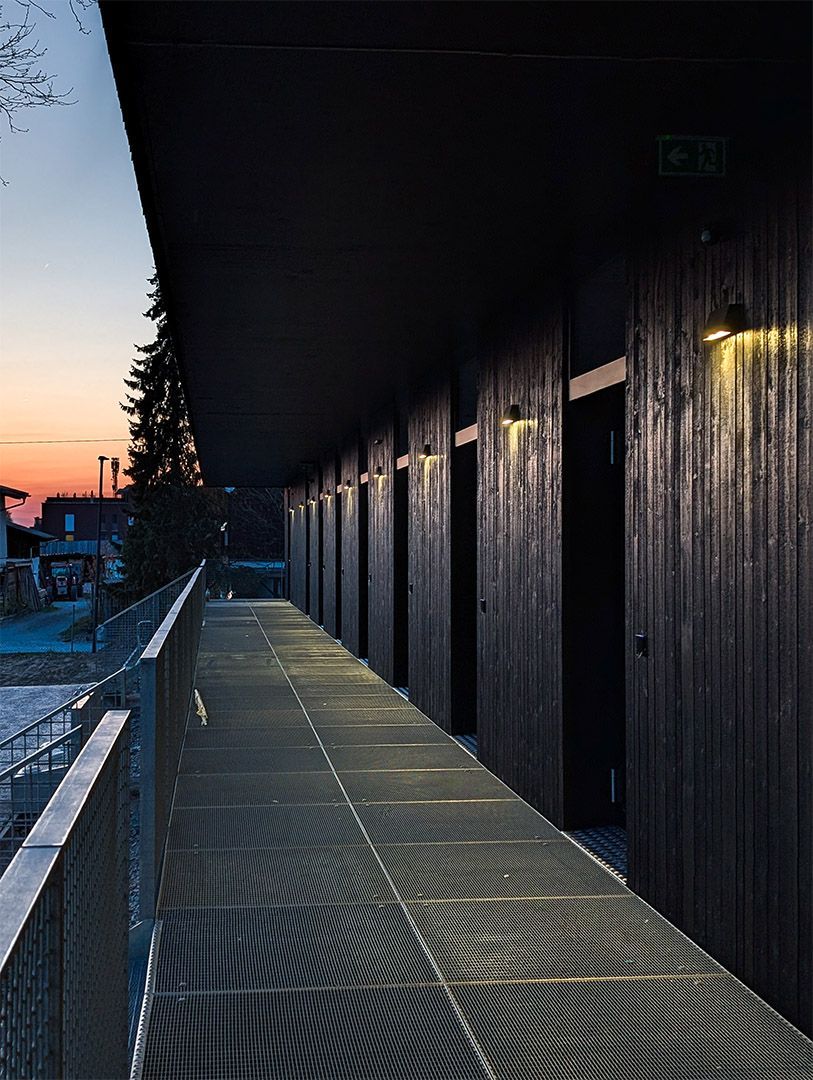 Ein langer Gehweg führt zu einem Gebäude mit einem Sonnenuntergang im Hintergrund.