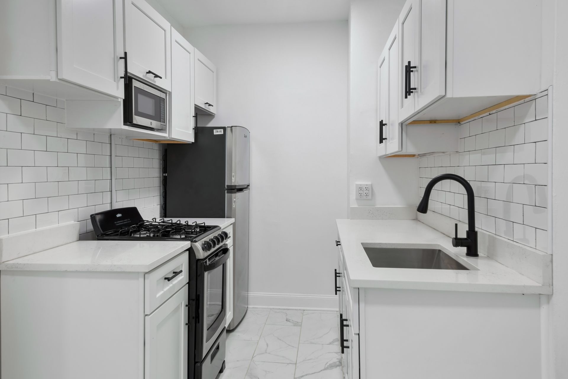 A small, white kitchen with appliances, including a microwave, stove, and refrigerator.