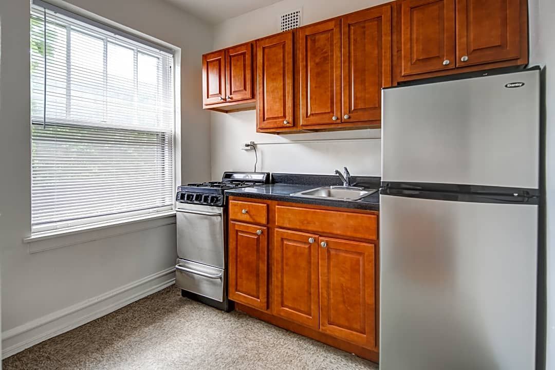 Small kitchen with brown cabinets, stainless steel appliances, and a window with blinds.