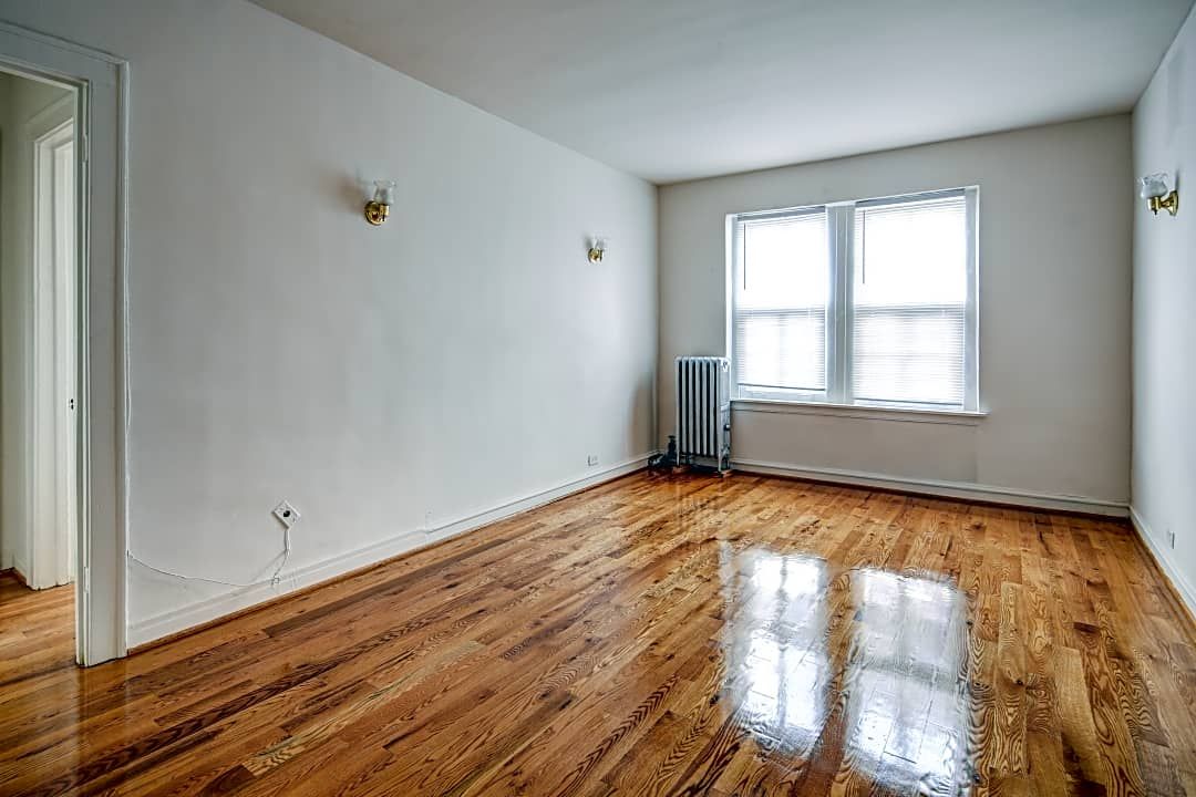 Empty room with hardwood floor, white walls, and a window.