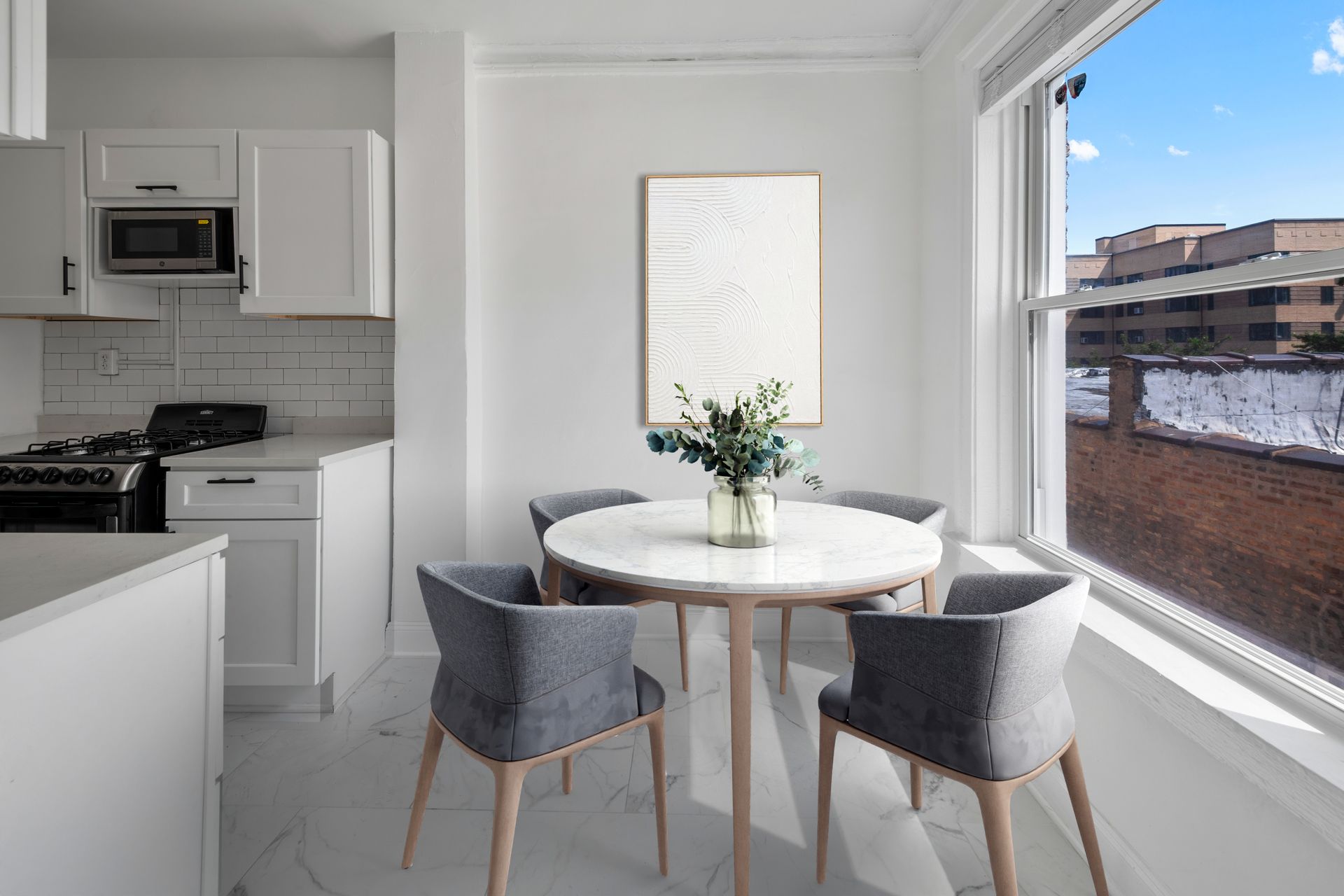 White kitchen with dining table, four gray chairs, and a window with cityscape view.