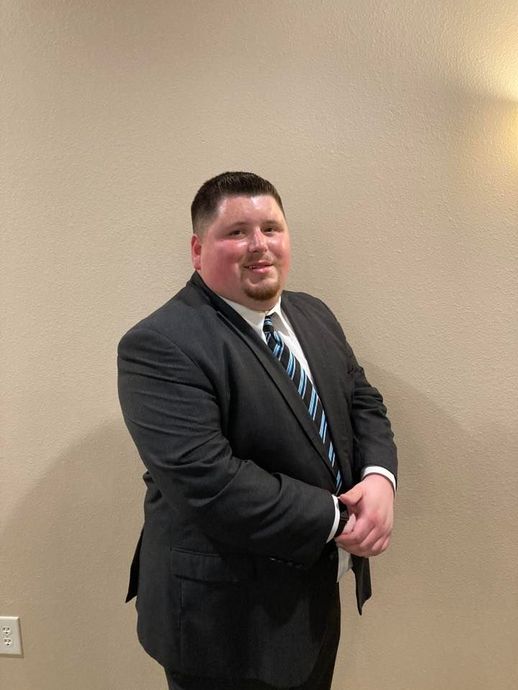 A man in a suit and tie is standing in front of a wall.