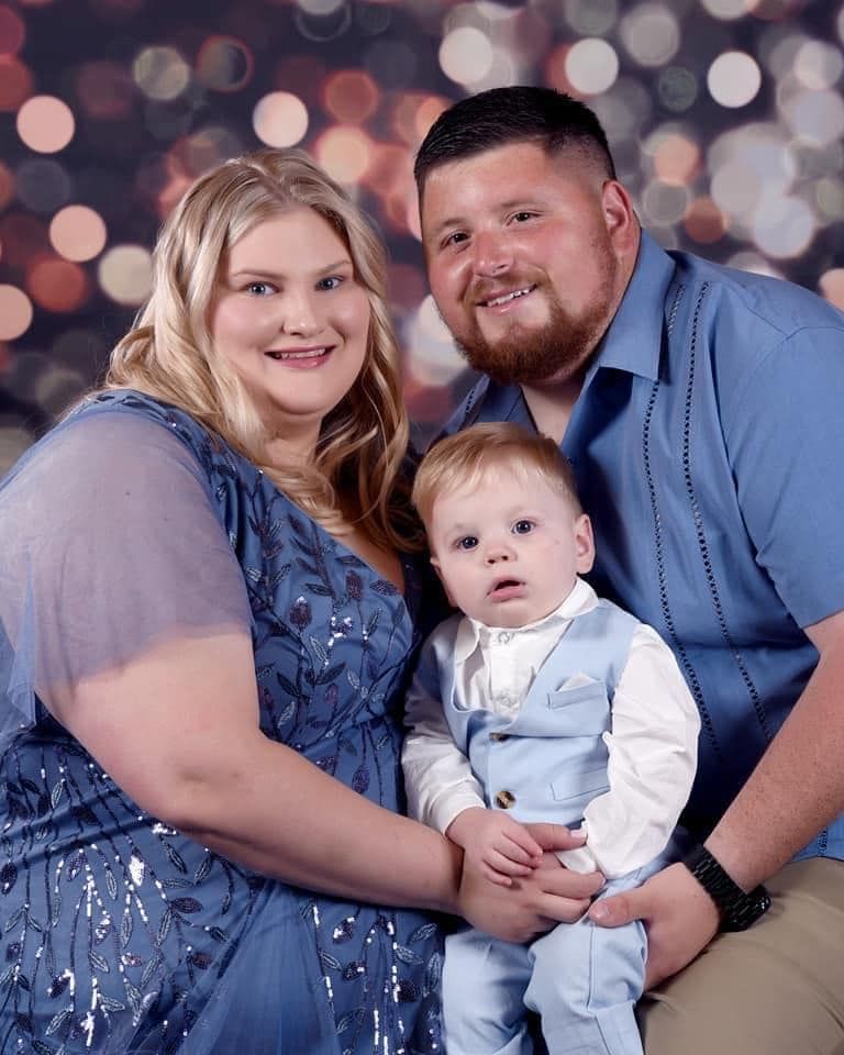 A man and a woman are posing for a picture with a baby.