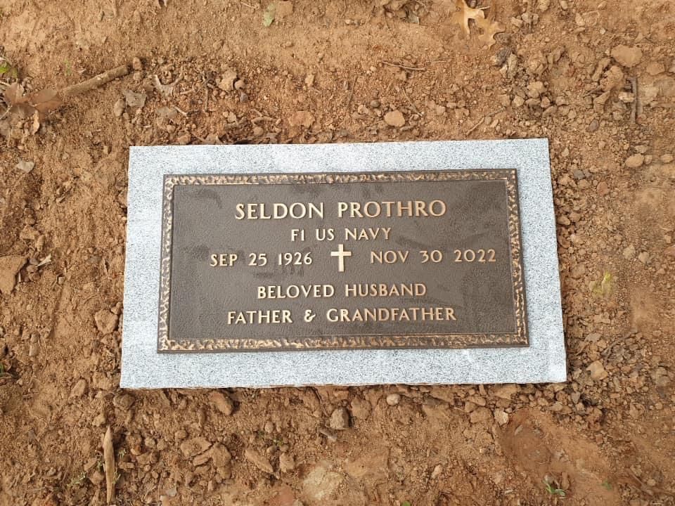 A gravestone for seldon protiro is sitting in the dirt.