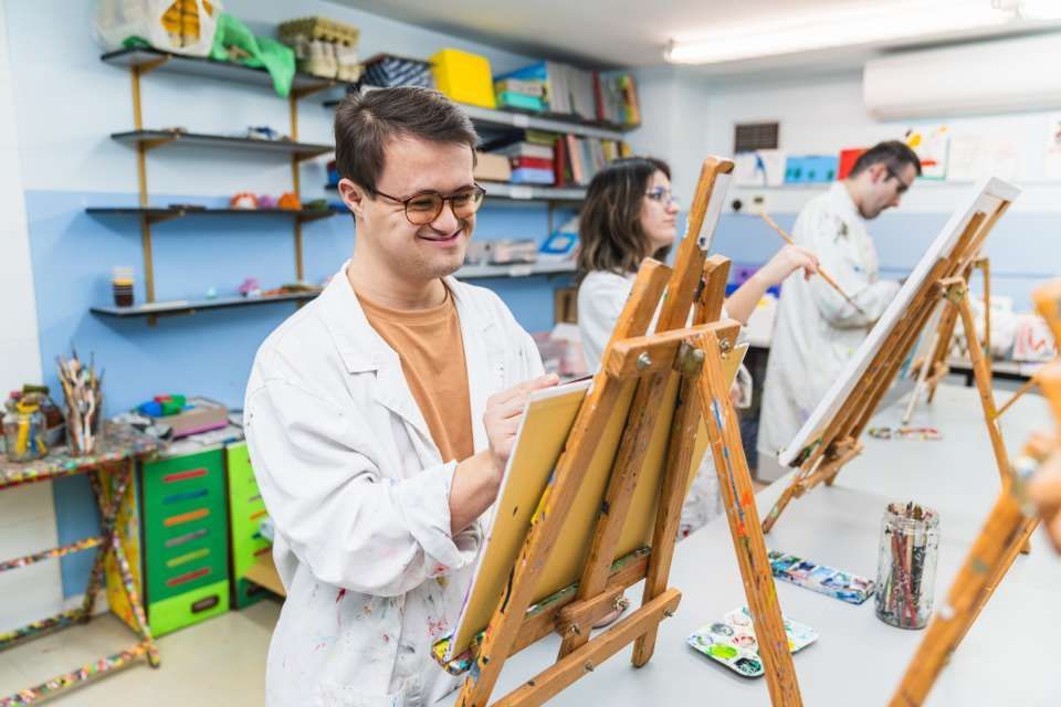 Man with Down syndrome paints with focus in an inclusive art class