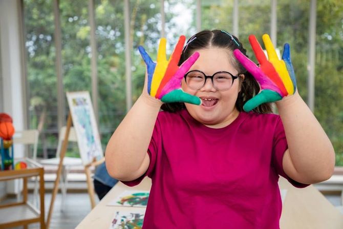 Young girl painting colourful on hand for creative and learning arts