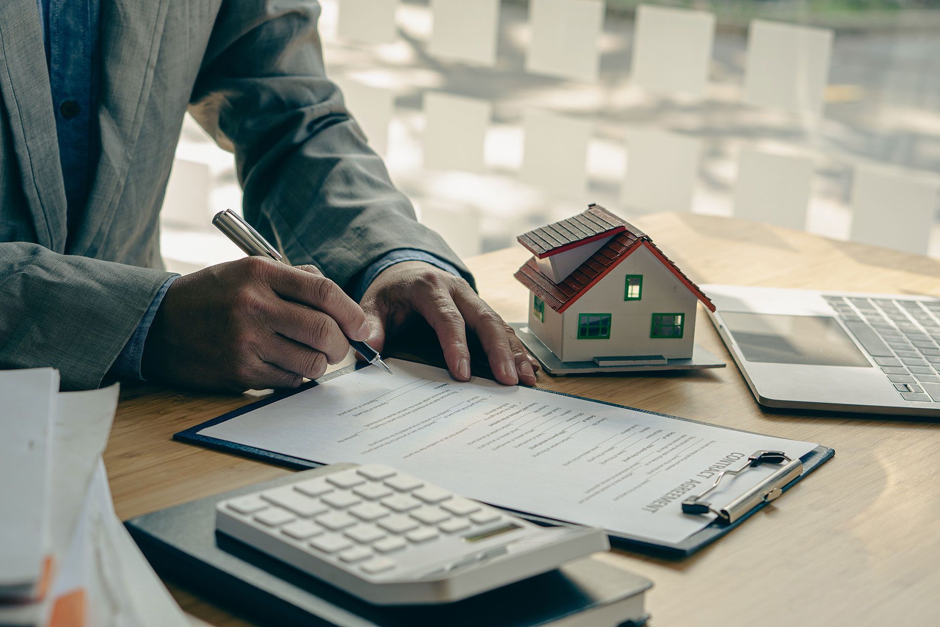 Businessman's signature on documents, checks, and documents in real estate investment projects on the desk. Sales report on the mortgage agent market in real estate concepts.