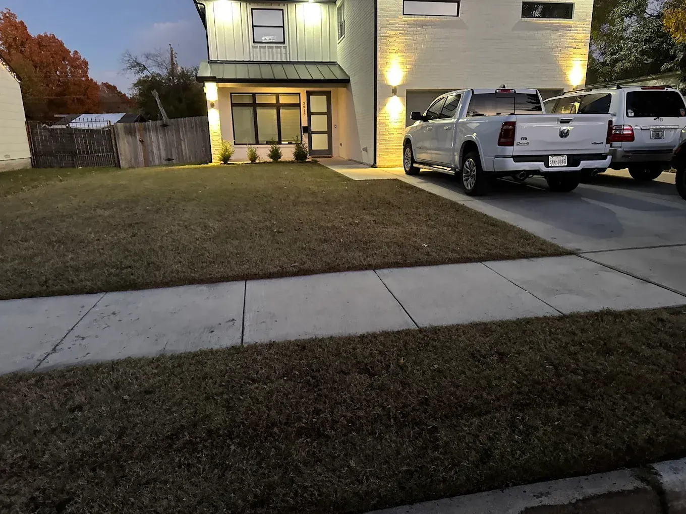 Two-story modern home with a white pickup truck in the driveway; a lawn and sidewalk are in the foreground.