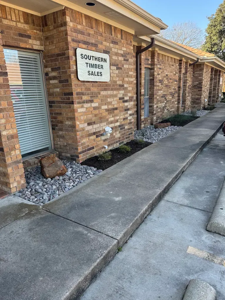 Exterior of a brick building with a concrete walkway. Sign reads 