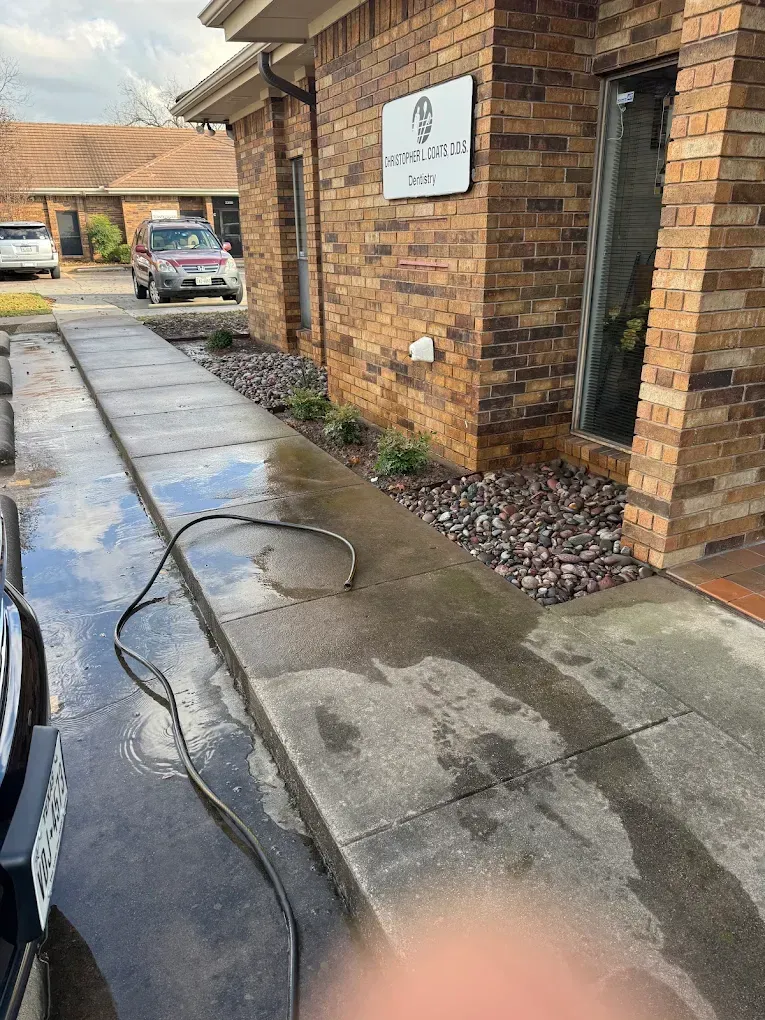 Wet concrete walkway next to brick building with a sign that reads 